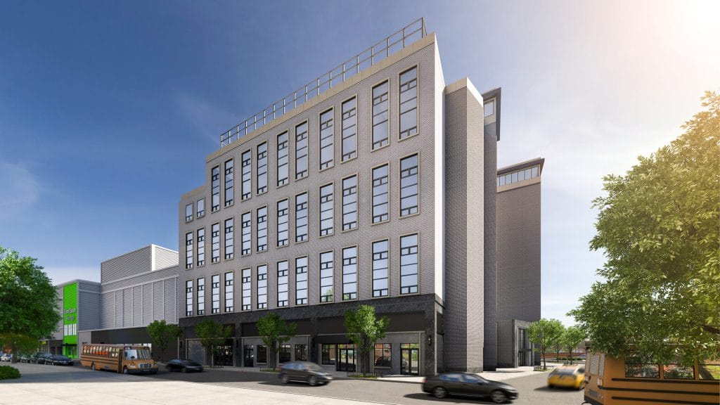 A sleek, multi-story building under a clear blue sky, boasting numerous large windows and ground-level storefronts. In the foreground, trees and a few vehicles, including a distinctive yellow school bus, enhance the urban scene.
